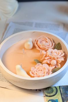 a white bowl filled with water and flowers on top of a table next to money