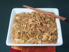 a white plate topped with noodles next to chopsticks