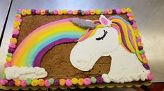 there is a decorated cake with a unicorn on the front and rainbow in the back