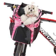 a small white dog sitting in the back of a pink bag on top of a bike