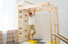 a man standing on top of a bunk bed in a room with yellow and white rugs