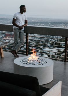 a man standing on top of a balcony next to a fire pit