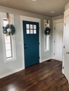 an empty room with two blue doors and wreaths on the front door's windows