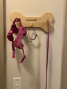 there is a pink leash hanging on the wall next to a wooden sign that says cannott