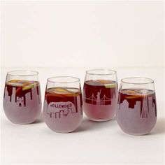 four wine glasses with different colored liquids in them