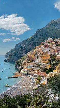 the beach is lined with colorful houses and boats in the water, along with mountains