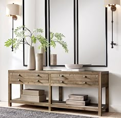 a wooden table with two vases on top of it next to a wall mounted mirror