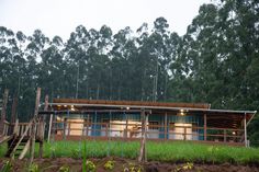 a wooden house sitting on top of a lush green hillside covered in trees and grass