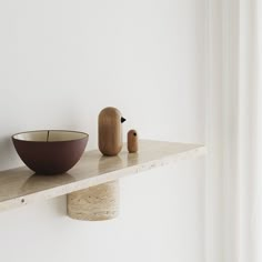 a bowl on a shelf next to a wooden bird figurine sitting on top of it