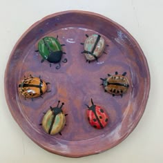 four different colored ladybugs sitting on top of a purple plate in the shape of a circle