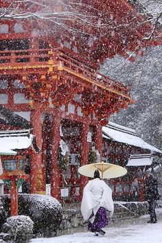 two people walking in the snow with umbrellas