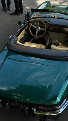 the interior of a green sports car parked in a parking lot with people standing around