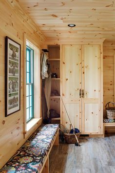 a room with wooden walls and flooring has a bench in front of the closet