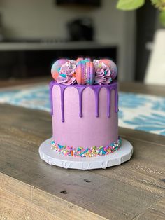 a purple cake with sprinkles and decorations on it sitting on a table