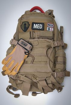 an army backpack with gloves and medical items on it's back pocket, against a white background