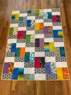 a multicolored patchwork quilt is on the floor next to a wooden floor