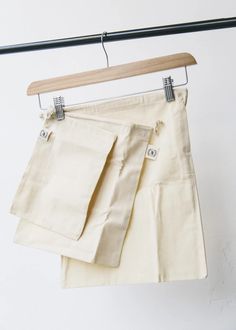 a pair of white pants hanging on a clothes line with a wooden hanger in front of them