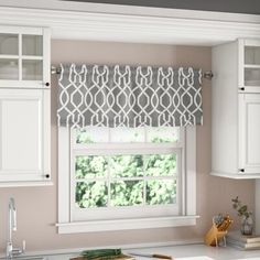 a kitchen with white cabinets and a window in the center, along with an island countertop