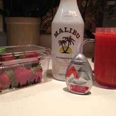 some strawberries are next to a bottle of juice on a counter top with other ingredients