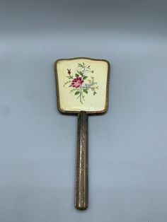 a decorative metal object with flowers painted on it's sides and a gold frame