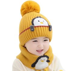 a little boy wearing a yellow hat and scarf with a penguin on it's head