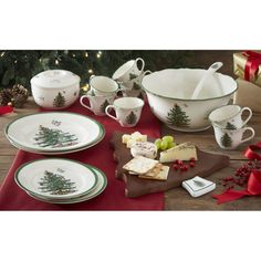 a table topped with plates and bowls filled with food next to a christmas tree decoration