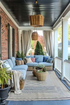 a covered porch with blue couches and potted plants