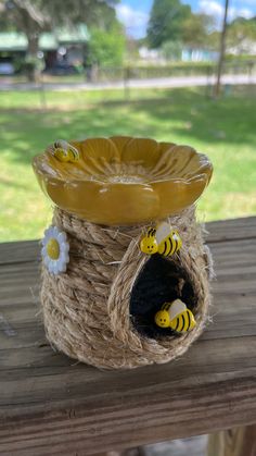 a yellow and black vase sitting on top of a wooden table next to a flower pot