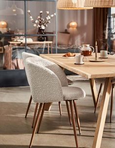 a wooden table with two chairs and coffee cups on it