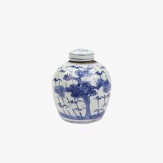 a blue and white vase with flowers on it's lid sits against a white background