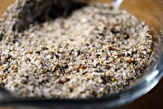 a bowl filled with some kind of food on top of a wooden table next to a spoon