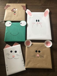 four paper bags with faces and ears on them sitting on a wooden floor next to each other