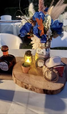 a table topped with a vase filled with flowers next to bottles of wine and candles