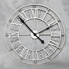 a large metal clock with roman numerals on it's face and hands