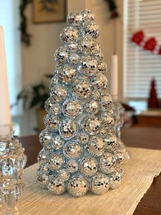 a christmas tree made out of glass balls on a placemat with candles in the background