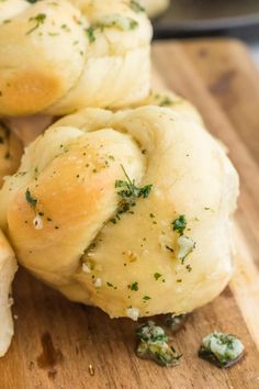 rolls with herbs on them sitting on a cutting board