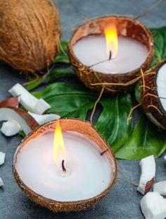 two coconuts with burning candles in them next to some cut up coconuts and leaves