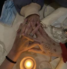 two people holding hands over a table with wine glasses and candles in front of them