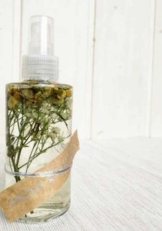 a bottle filled with lots of green plants sitting on top of a white tablecloth