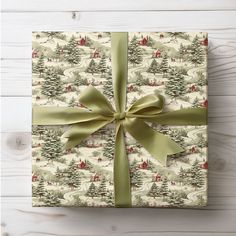 a wrapped present with a green bow on it's side sitting on a wooden table