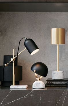 two black lamps sitting on top of a table next to books and other decor items