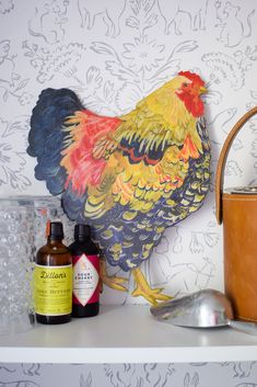 a rooster painted on the side of a wall next to bottles and utensils