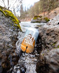 a can of beer sitting on top of a rock in the middle of a river