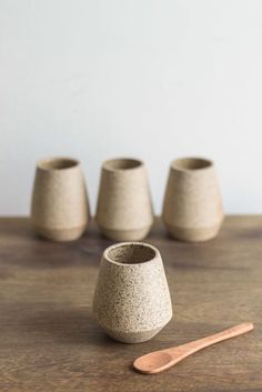 four small cups and a wooden spoon on a table