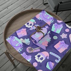 a table topped with purple wrapping paper covered in pink and blue items on top of a wooden table