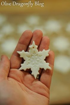 a hand holding a small white snowflake ornament