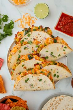 tortillas on a plate with salsa, limes and other condiments