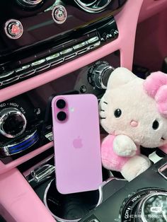 a pink iphone case sitting on top of a car dashboard next to a stuffed animal