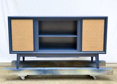 an old blue cabinet with wicker doors and wheels is on display in front of a white wall