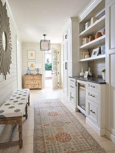 a long hallway with white cabinets and an area rug on the floor in front of it